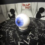 3D eyeball on a table with 2D illustrations around it.