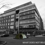 Black and white photo of office building with colour wigwam setup in front of building.